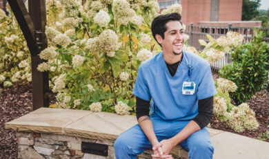 Male nurse sitting on a bench outside, smiling