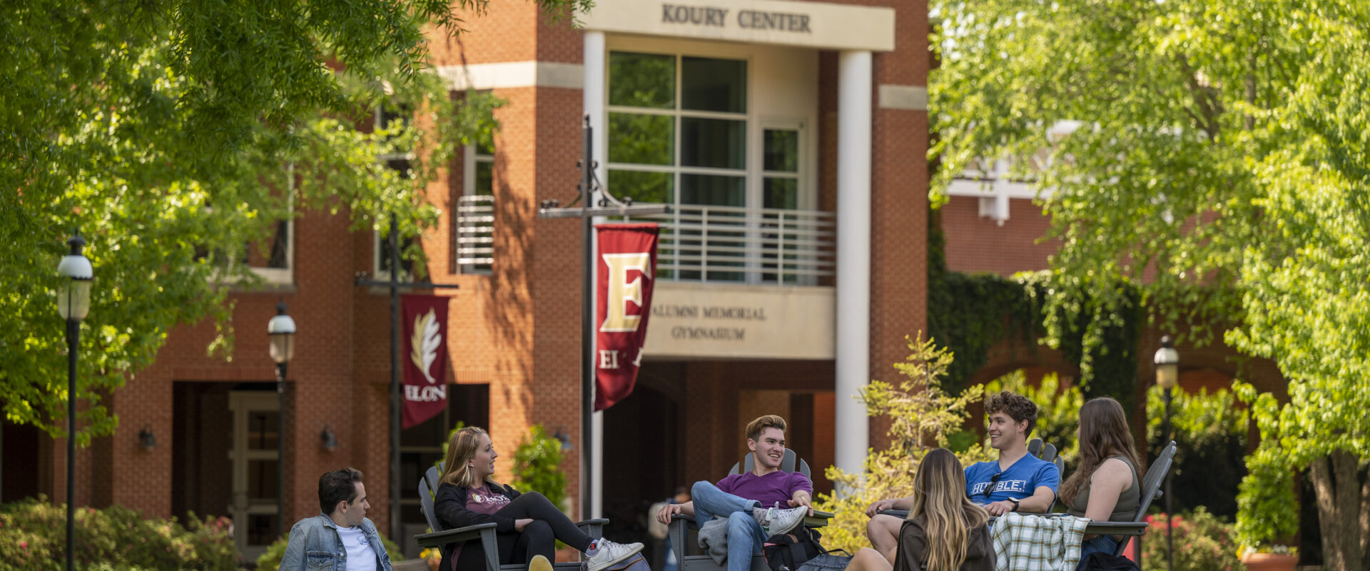 Group of students sit in lawn chairs outside the Koury Center at Elon University