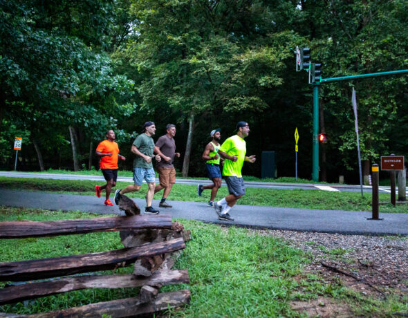 A group of men jog through a park in the Carolina Core