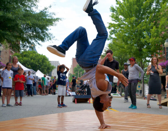 Person breakdancing outside in front of crowd.