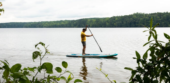 Person paddleboarding on serene lake.