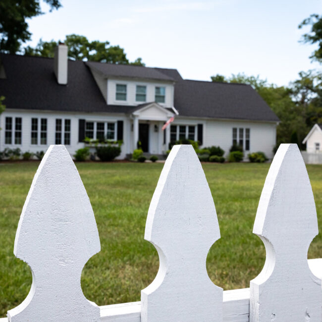 Zoomed in white-picket fence and blured house in the background.